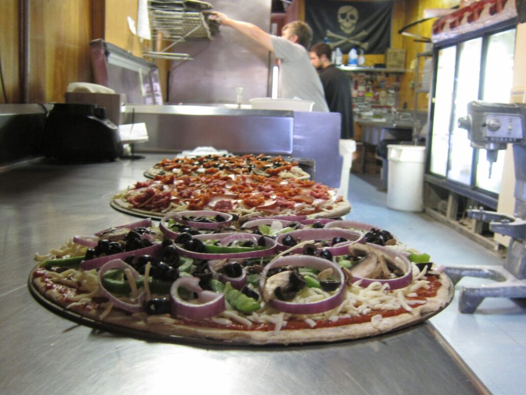 An image of a lineup of three various pizzas waiting to go into the oven at Big Tomato Pizza.