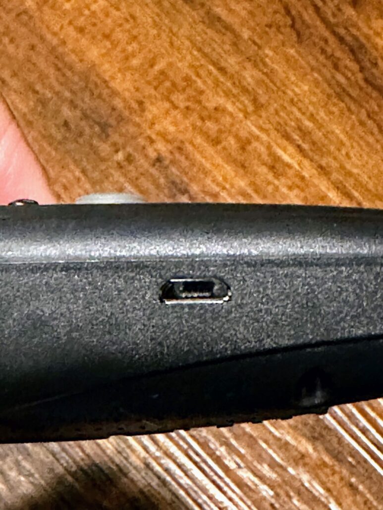 A close-up of the TOKEGO Ultrasonic Dog Bark Deterrent device, showing the power button and charging port.