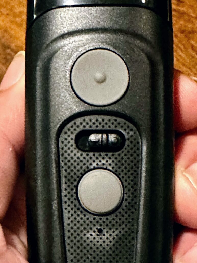 A close-up showing the power button, flashlight button, and mode toggle switch.