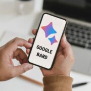 Feature image for the post, "Google Bard: A Comprehensive Guide to Using Google's Answer to ChatGPT" featuring a pair of hands holding a phone displaying the Google Bard Logo.