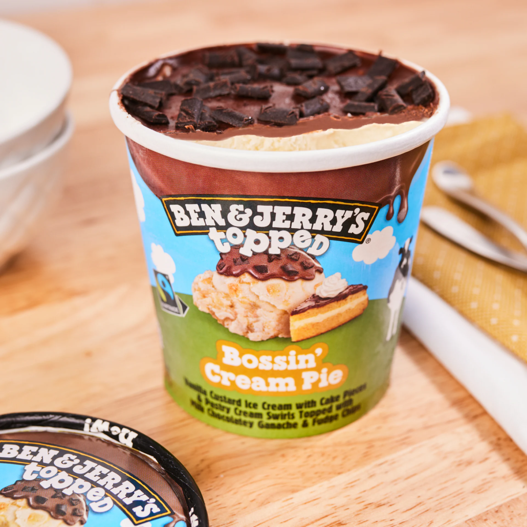 Open pint of Ben & Jerry’s Bossin’ Cream Pie ice cream showing thick chocolate topping and custard base