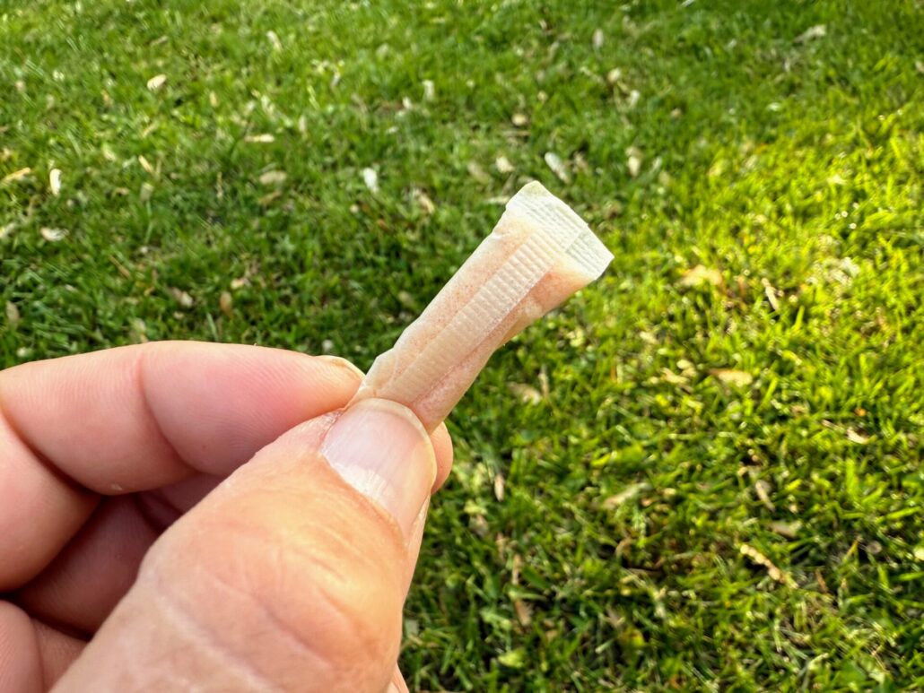 Close-up of a single Juice Head nicotine pouch held between fingers
