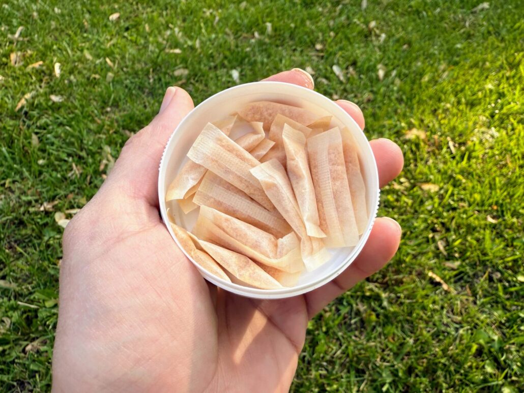 Open can of Juice Head Pouches held in hand, showing several nicotine pouches inside