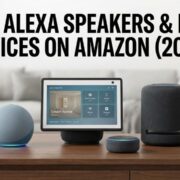 A collection of Amazon Echo devices on a wooden desk, including an Echo Show 15 smart display, Echo Studio speaker, a spherical Echo, and an Echo Dot, next to a smartphone running the Alexa app. The text overlay reads 'BEST ALEXA SPEAKERS & ECHO DEVICES ON AMAZON (2025)'.