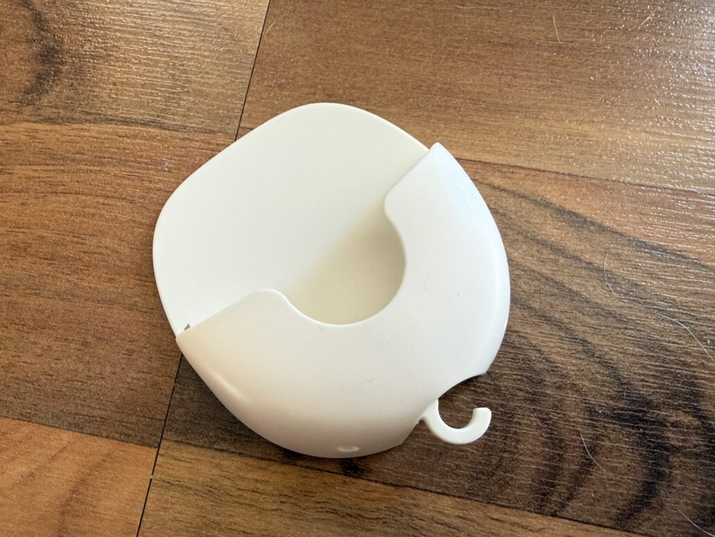 White plastic mounting accessory for the Blink Mini 2K+ security camera shown on a wooden floor.