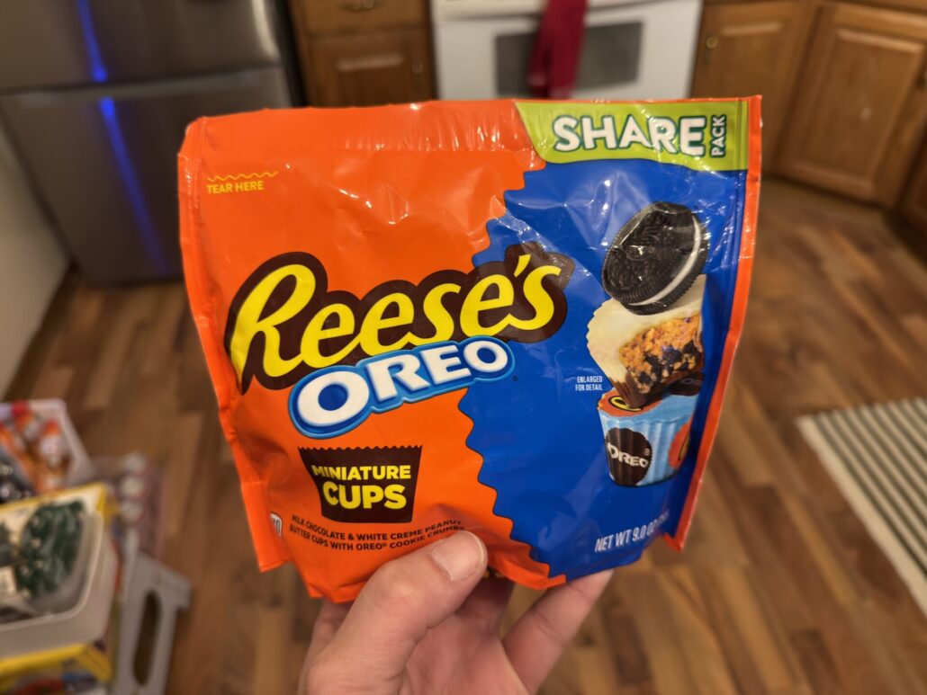 Reese’s Oreo Miniature Cups share pack bag held in hand in a kitchen
