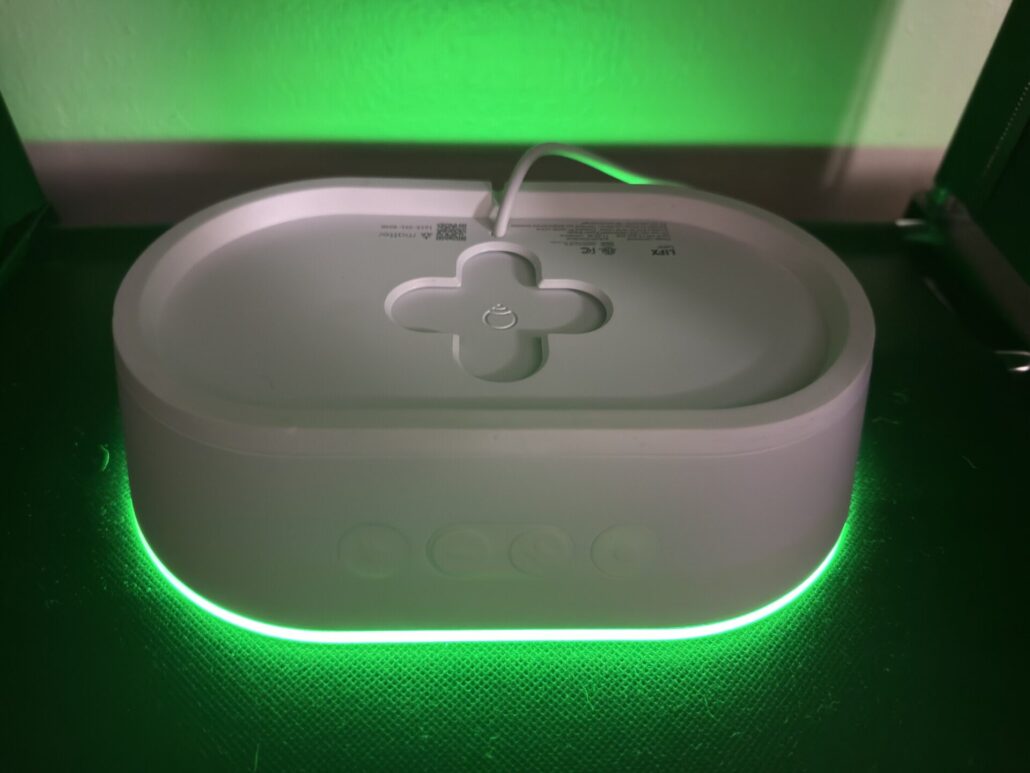 LIFX Luna resting face down and casting a green glow around its edges on a dark surface