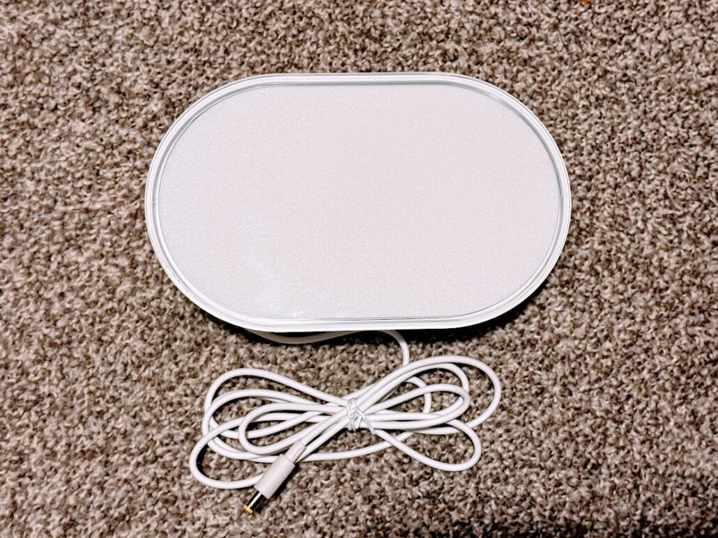 LIFX Luna smart lamp lying flat on a carpet with its white power cable coiled beside it