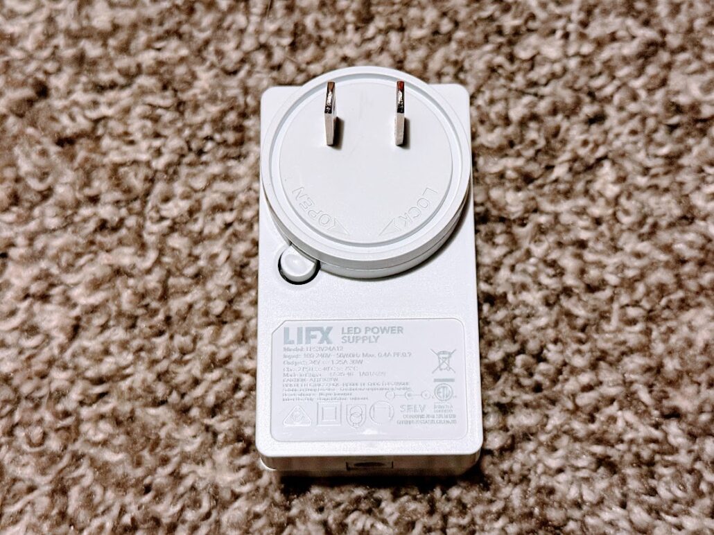 White LIFX Luna LED power supply lying label-up on a carpet with its cable attached
