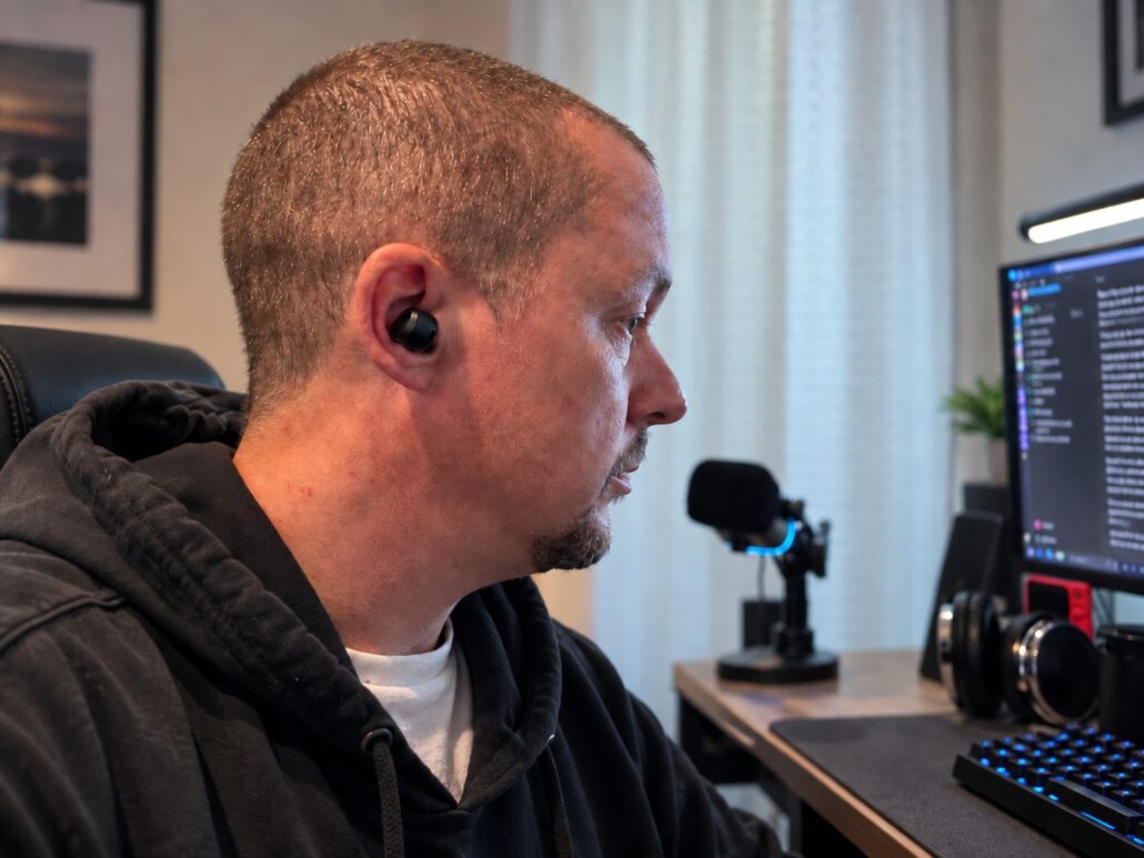 Tony wearing a TOZO NC9 Pro earbud while working at his desk