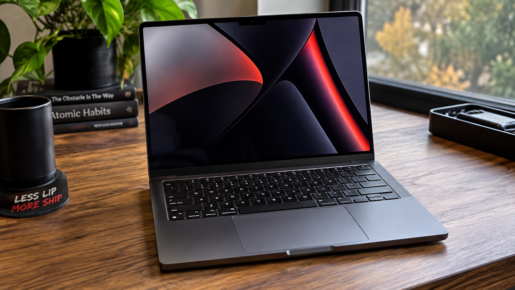 Space Black 14-inch MacBook Pro M5 sitting unplugged on a wooden desk near a window